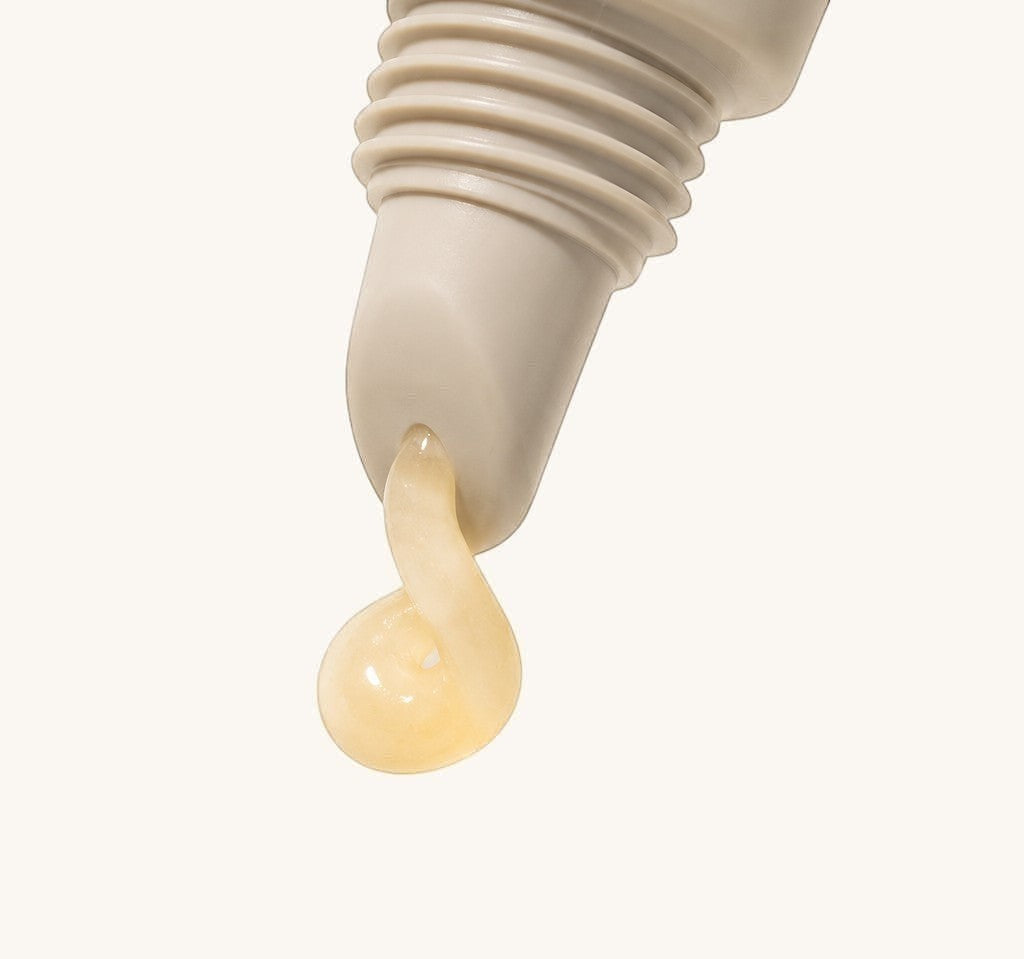 Close-up of a dropper with a drop of cream on a light background