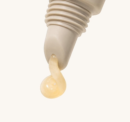 Close-up of a dropper with a drop of cream on a light background